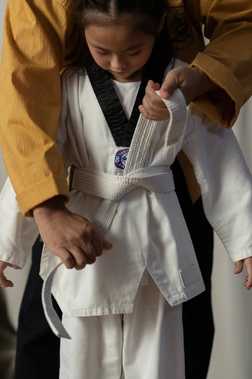 a person holding the belt of a girls taekwondo uniform